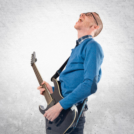 Young man playing guitar over white backgroundの写真素材