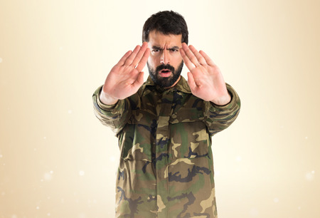 Soldier making stop sign over white backgroundの写真素材