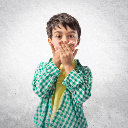 Kid covering his mouth over white backgroundの写真素材