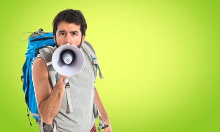 Backpacker shouting by megaphone over white backgroundの写真素材