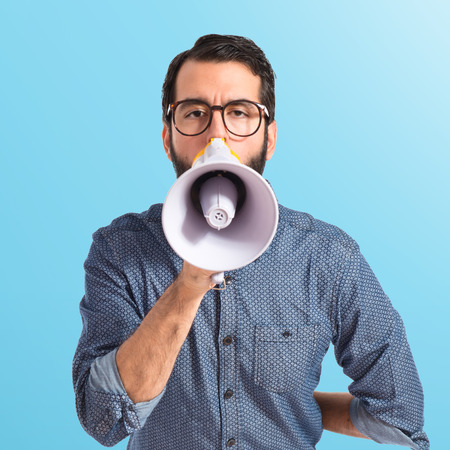Young hipster man shouting by megaphoneの写真素材