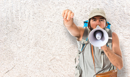 Backpacker shouting by megaphone over white backgroundの写真素材