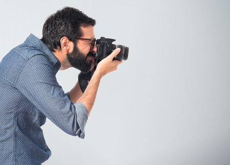 Young hipster man photographing over white backgroundの写真素材