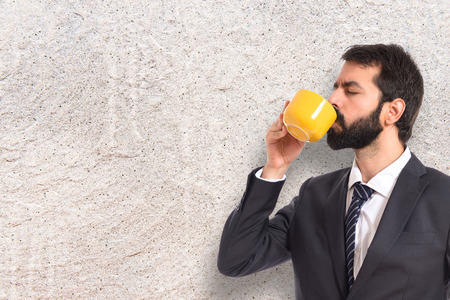 Businessman drinking coffee over white backgroundの写真素材