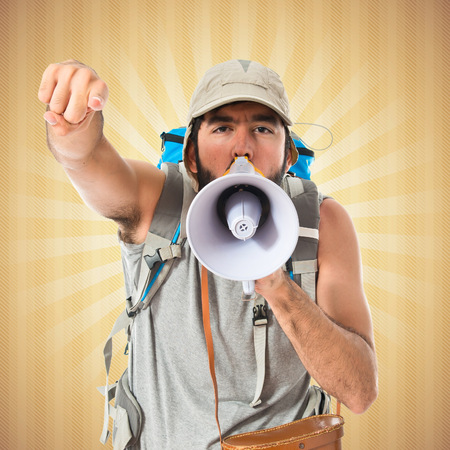 Backpacker shouting by megaphone over white backgroundの写真素材