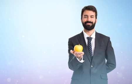 Businessman holding an apple over whiteの写真素材