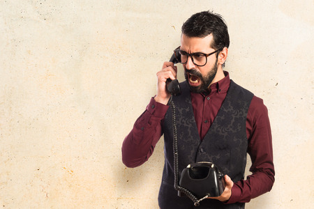 Man wearing waistcoat talking to vintage phoneの写真素材