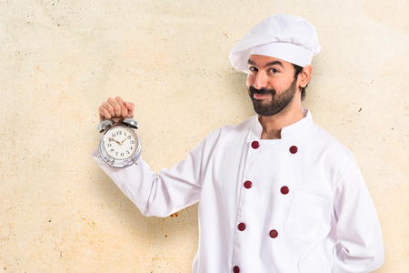 Chef holding a clock over white backgroundの写真素材