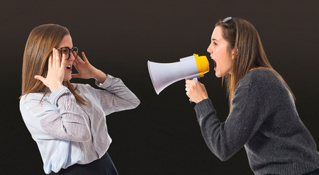Girl shouting at her sister by megaphoneの写真素材