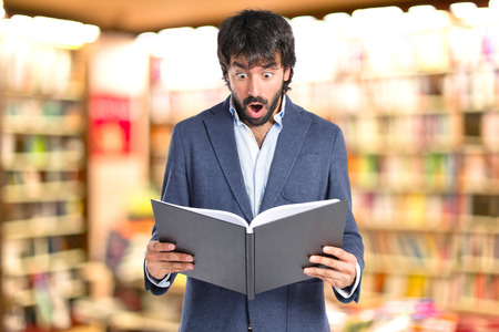 Surprised man reading a book over white backgroundの写真素材