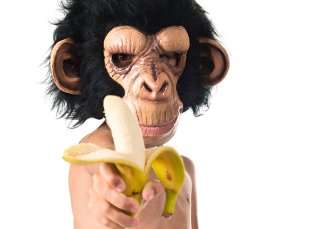 Child with monkey mask holding a bananaの写真素材