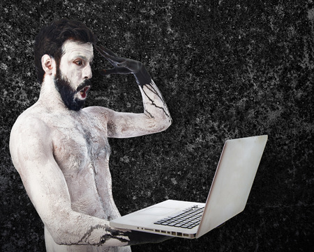 Surprised primitive with laptopの写真素材