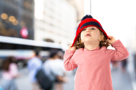 Little girl puttining on a Christmas hat over white backgroundの写真素材