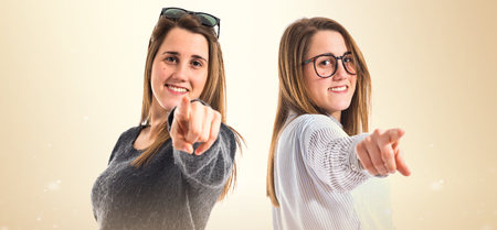 Twin sisters pointing to the frontの写真素材