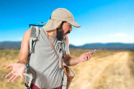 Surprised backpacker talking to mobile over white backgroundの写真素材