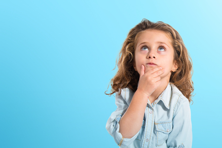 Blonde little girl thinking over white backgroundの写真素材