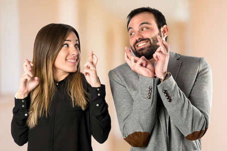 Couple with their fingers crossing over white backgroundの写真素材