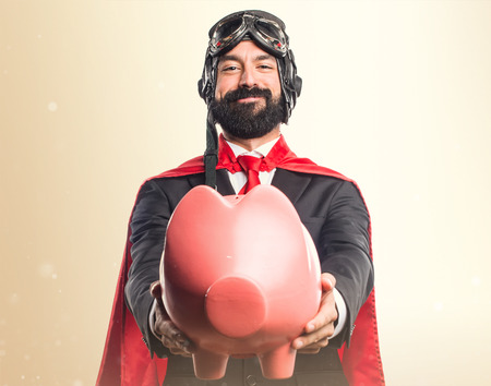 Super hero businessman holding a piggybankの写真素材