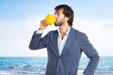 Businessman holding a cup of coffee over white backgroundの写真素材