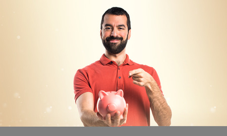Handsome man holding a piggybankの写真素材