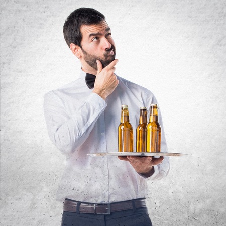 Waiter with beer bottles on the tray thinkingの写真素材