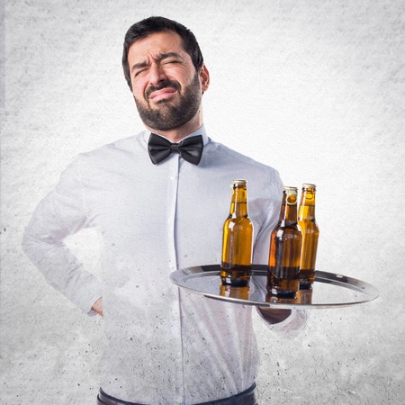 Waiter with beer bottles on the tray with back painの写真素材