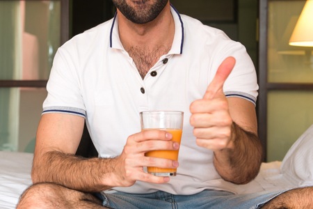 Man drinking orange juice in a hotelの写真素材