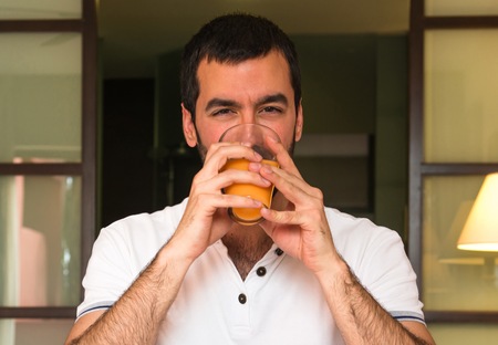 Man drinking orange juice in a hotelの写真素材