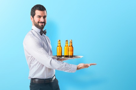 Waiter with beer bottles on the tray presenting somethingの写真素材