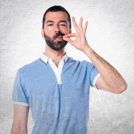 Man with blue shirt making silence gestureの写真素材