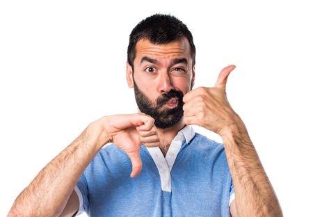 Man with blue shirt making good-bad signの写真素材