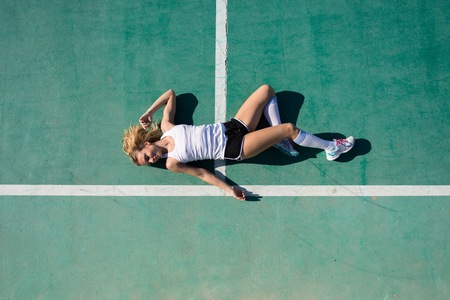 Pretty woman in football field resting in the floorの写真素材