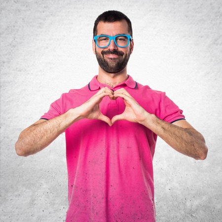 Man with colorful clothes making a heart with his hands on grey textured backgroundの写真素材