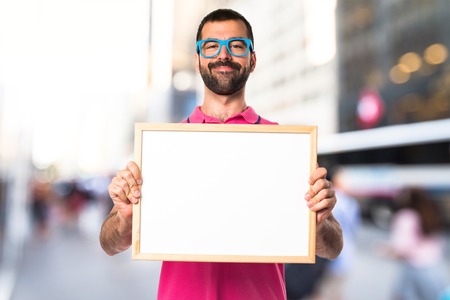Man with colorful clothes holding an empty placardの写真素材