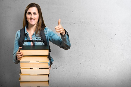 Teen student girl with a lot of books and with thumb upの写真素材