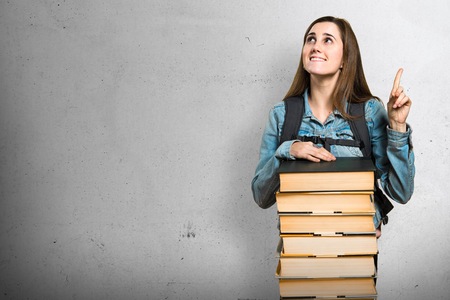 Teen student girl with a lot of books and pointing upの写真素材