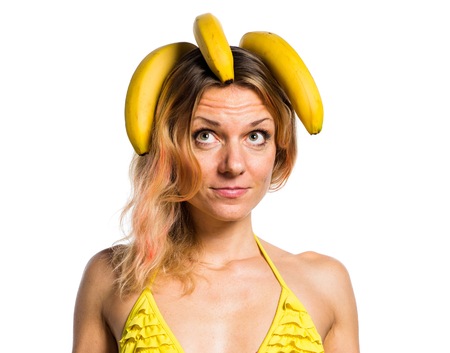 Beautiful blonde woman in bikini holding bananasの写真素材
