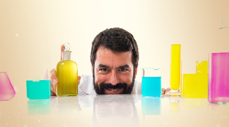 Scientist hiding behind test tubes on ocher backgroundの写真素材