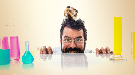 Crazy scientist man with skull on ocher backgroundの写真素材