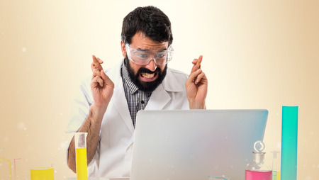Scientist man with his fingers crossing on ocher backgroundの写真素材