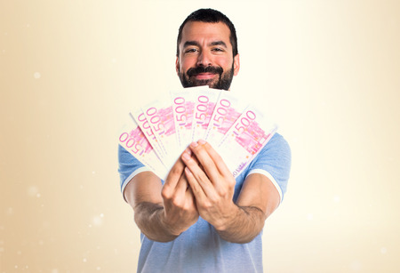 Man with blue shirt taking a lot of money on ocher background