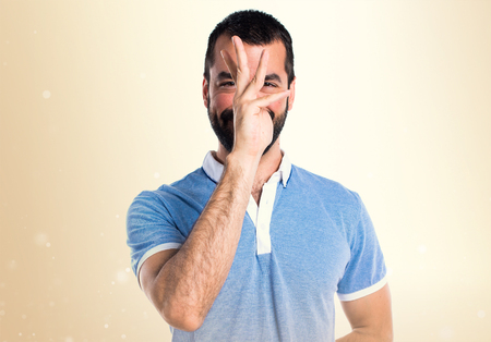 Man with blue shirt doing a joke on ocher backgroundの写真素材