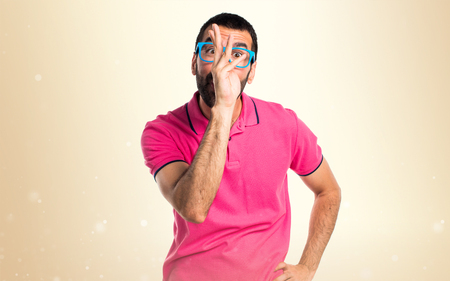 Man with colorful clothes making a joke on ocher backgroundの写真素材
