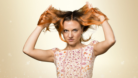 Pretty woman with orange hair on ocher backgroundの写真素材