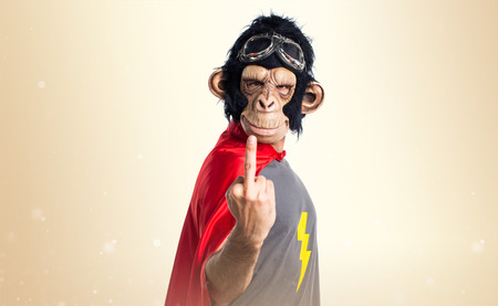 Superhero monkey man making horn gesture on ocher backgroundの写真素材
