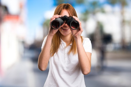 Happy Beautiful young girl with binoculars on unfocused backgroundの写真素材
