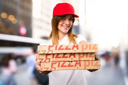 Happy pizza delivery woman on unfocused backgroundの写真素材