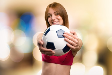 Young sport woman  holding a soccer ball on unfocused backgroundの写真素材