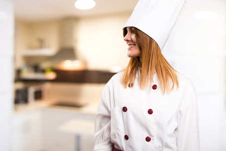 Beautiful chef woman looking lateral in the kitchenの写真素材