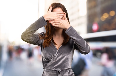 Beautiful young girl covering her face on unfocused backgroundの写真素材
